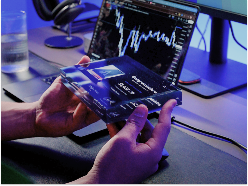 A guy holding a Funded account certificate from Funded Award with trading charts in the background 