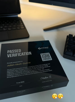 FTMO verification certificate on a desk with a laptop and keyboard in the background