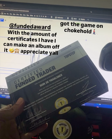 Hand holding a 'Certified Funded Trader' plaque from Funded Award in front of a computer screen with trading graphs in the background and text overlay.